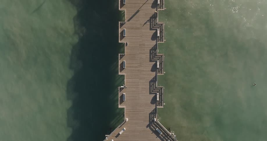People walk along the long pier on the beach