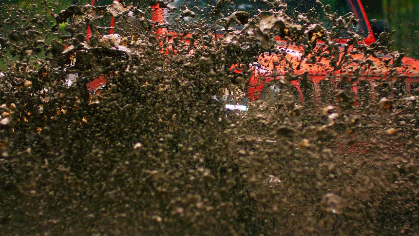 A jeep truck powers through a mud puddle