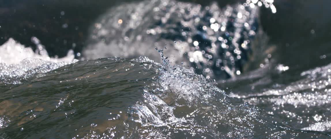 A closerange perspective captures the powerful flow of a river where water quickly moves and crashes producing a mixture of waves and scattered droplets
