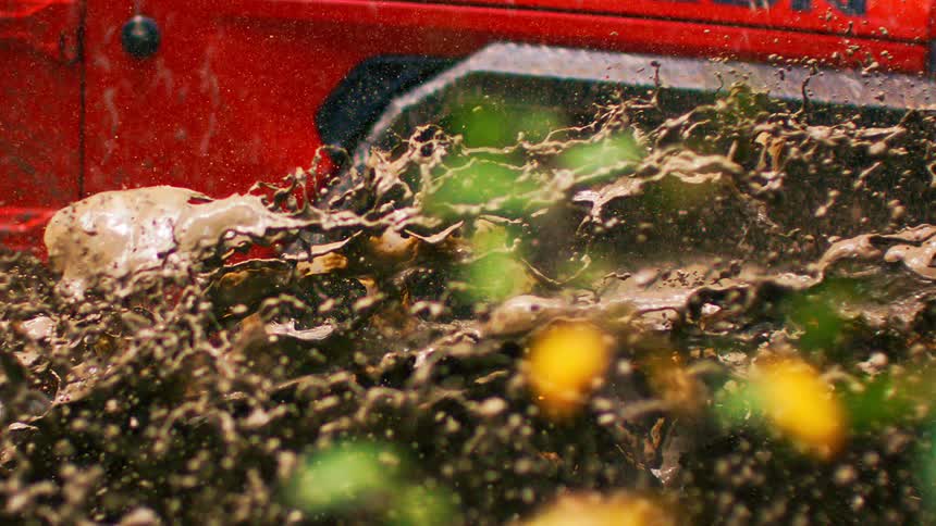 A red jeep rubicon powers through thick offroad mud with dirt splashing around the wheels