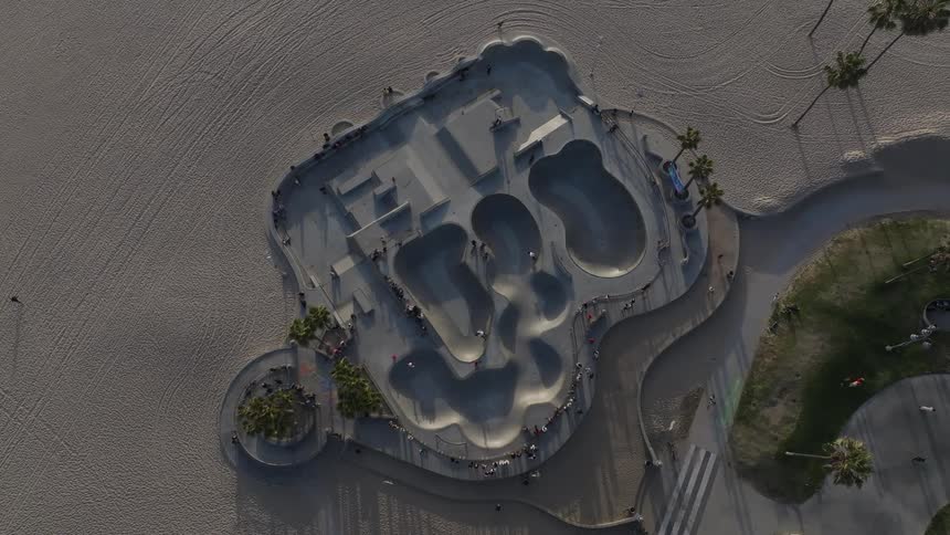 Aerial view of a poolshaped skateboard complex located in a beach area with people using the space
