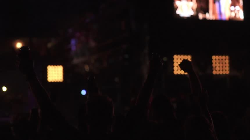 People are standing in a crowd holding up their phones