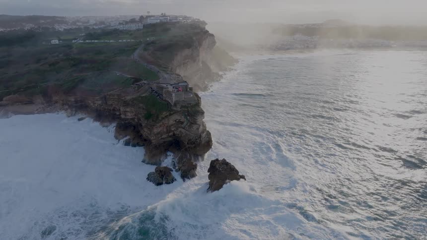 Aerial view of strong waves crashing onto rocky coastline