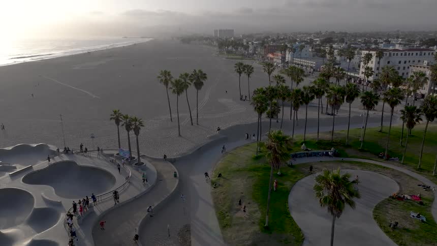 Aerial view of a skate park on the beach sand with a city in the background