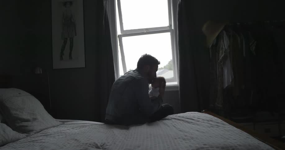 Man holds baby on a bed