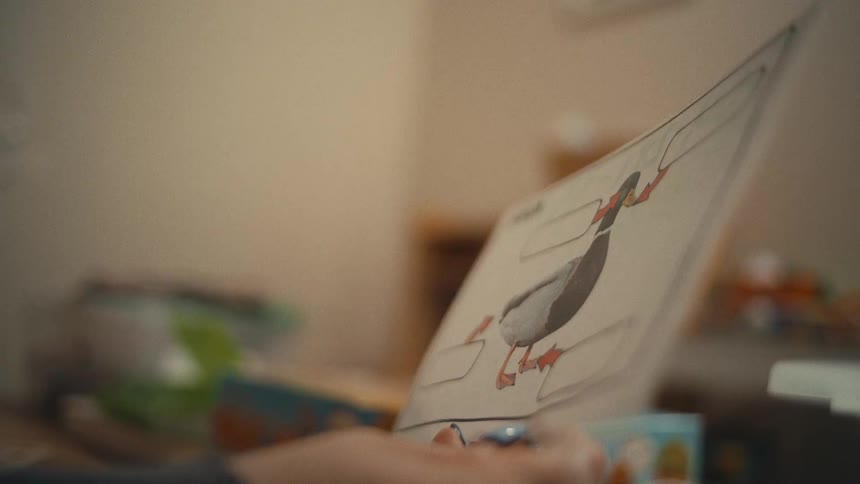 Person points to an image while interacting with a sheet of paper