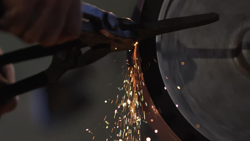 A person is using a grinder on a tool