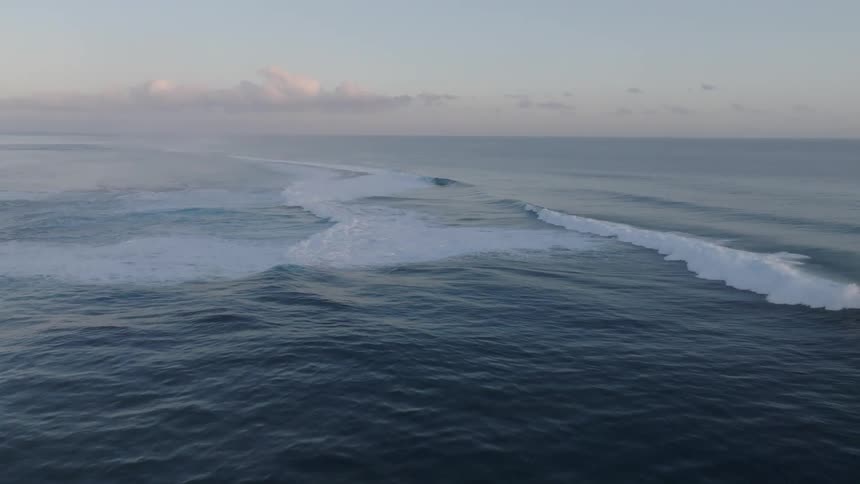 Large waves crash in the ocean at dusk