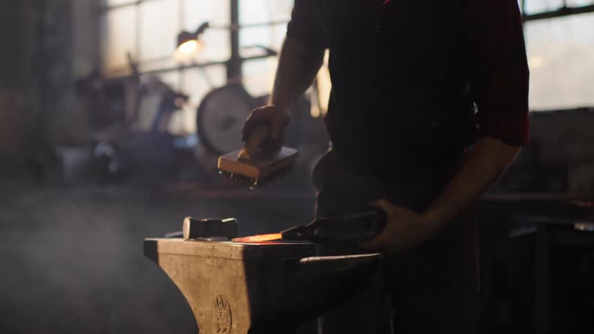 Person holding a hot iron and forging