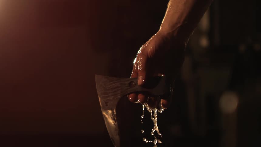 Arm with a tattoo pulling a freshly forged piece of iron out of the water