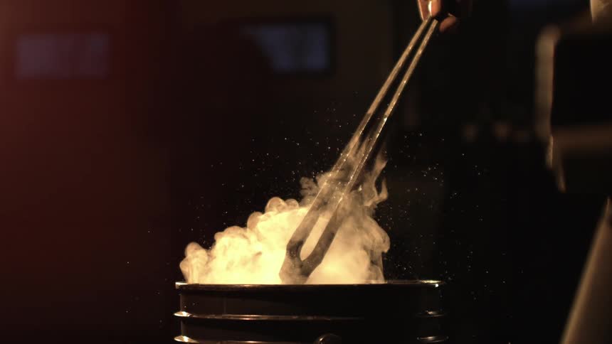 Hand holding a tool and taking it out of a bucket with smoke coming out