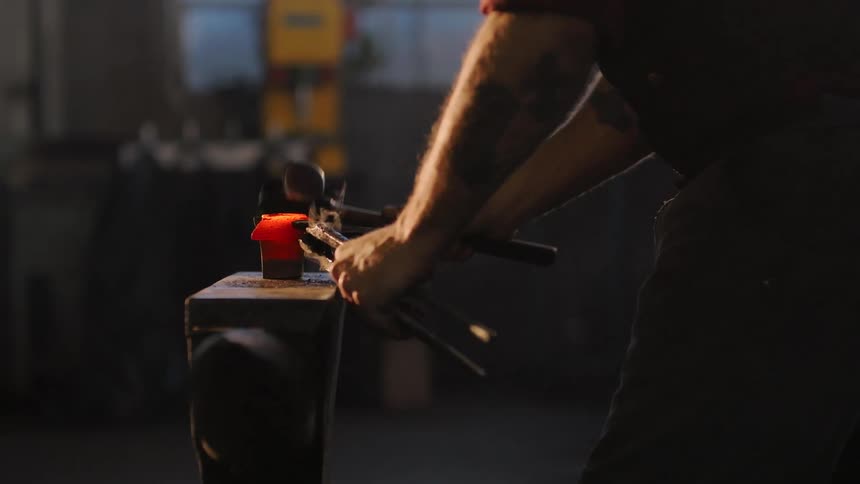 Man working iron with a hammer and tongs