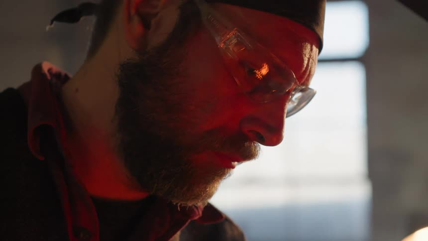 Concentrated man wearing goggles looking toward a fire