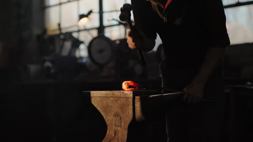 The blacksmith is hammering the iron on the anvil
