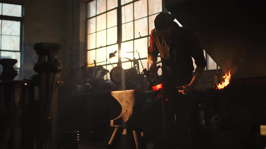 Man works with a heated iron on an anvil