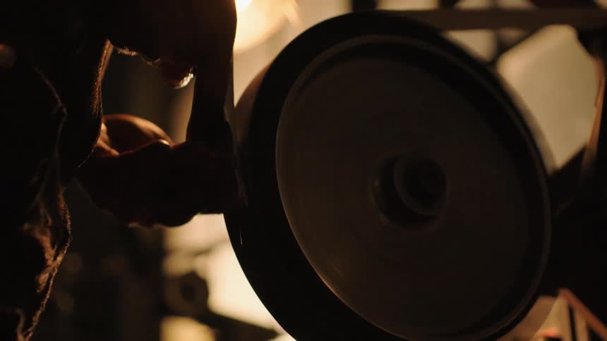 Man sharpens the head of an ax creating sparks