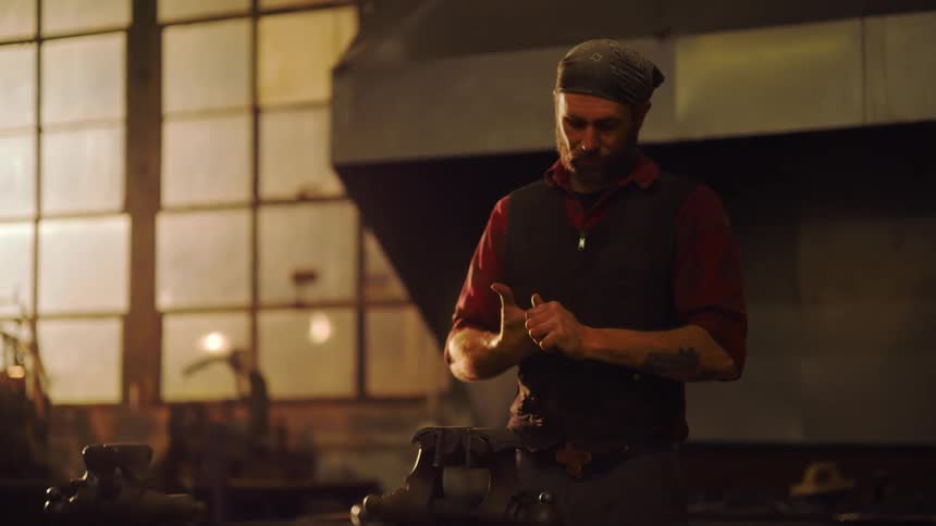 A man is standing in a workshop rubbing his hands together