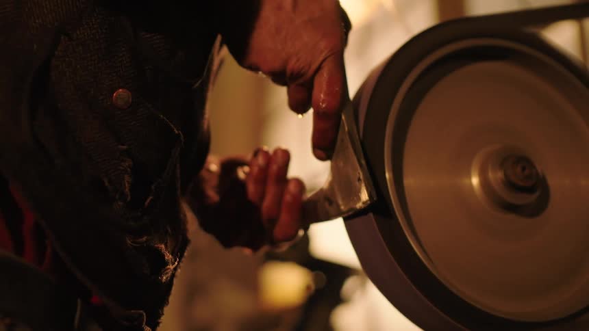 A worker polishing an axe blade using a machine