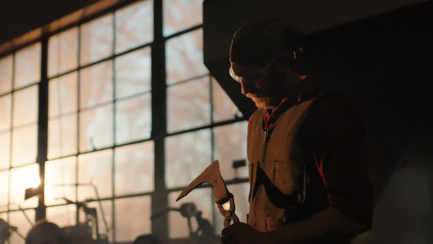 The blacksmith turns around with a piece of metal