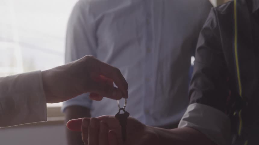 Realtor handing over the keys to a couple renting the apartment