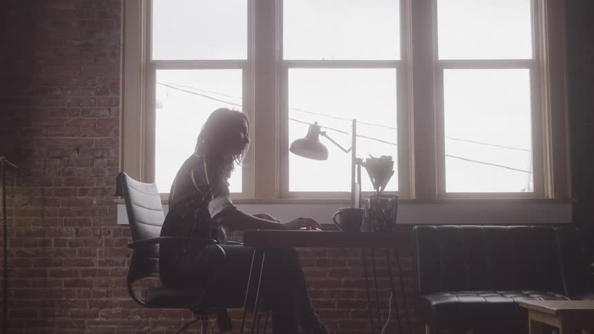 Girl sitting at a desk writing something then working on the computer