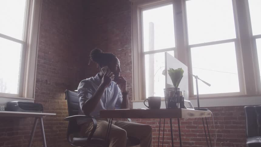 Boy talking on cell phone while sitting in front of a computer