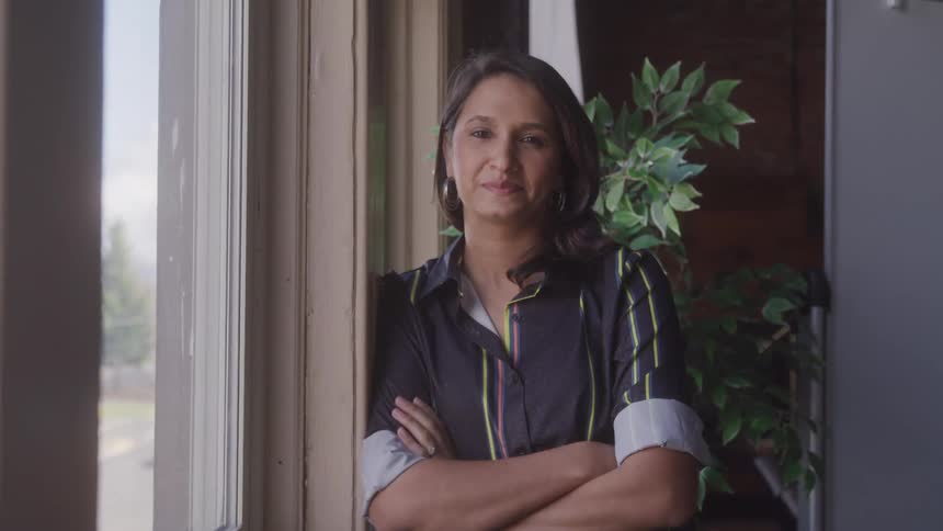 A woman leans against the window smiling