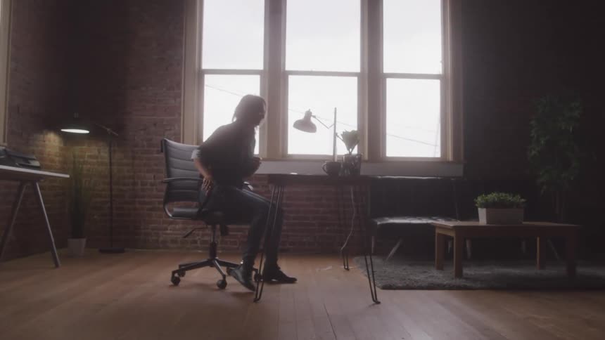 An artist walks towards her desk takes a sit and picks up her pencil