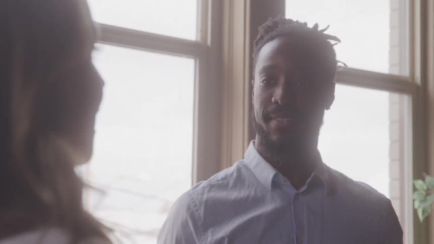 Man talking to a woman next to a window in an indoor space
