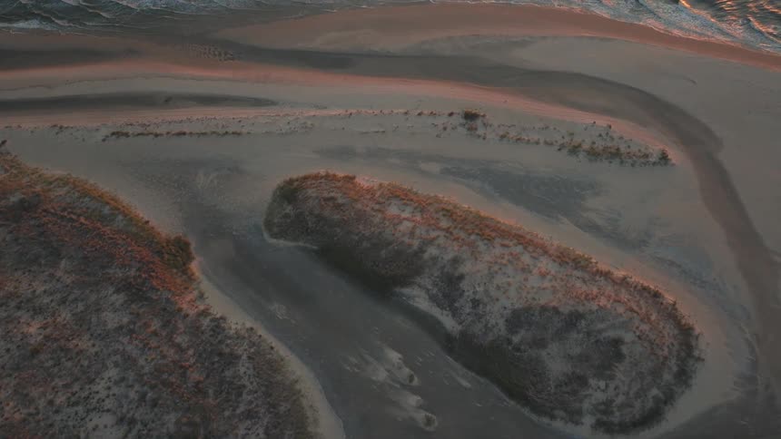 The camera is moving above the islands of sand and grass and vast areas of water