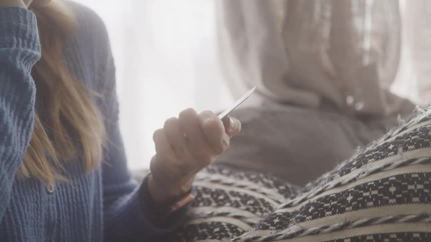 A woman is talking on the phone as she looks at her credit card