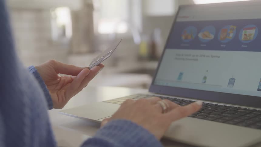Woman browsing a site on a computer with a credit card in her hand