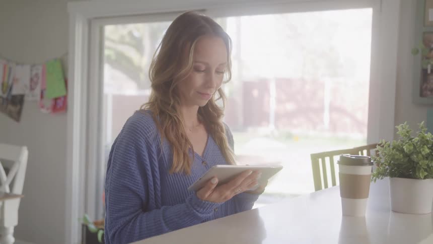 A footage of a lady operating a tablet indoor