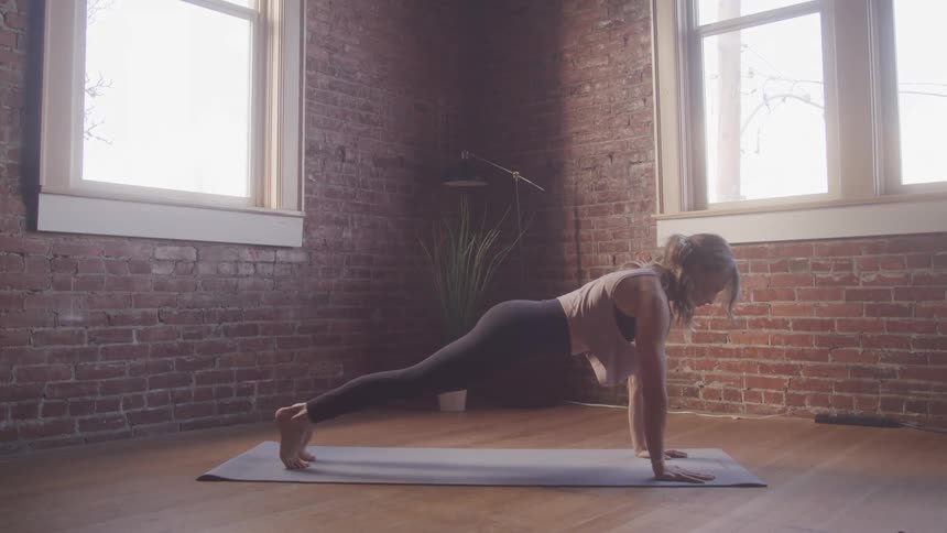 A woman is doing yoga by the window