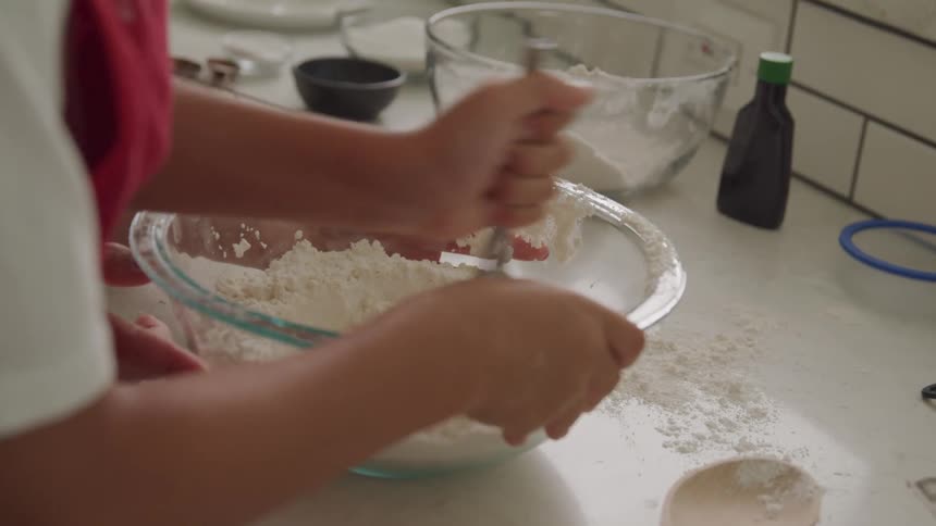A person is stirring a flour mixture in a bowl