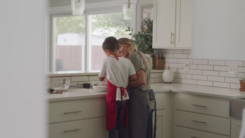 A mother helps her son cook in the kitchen