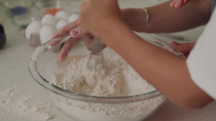 A woman holds a bowl while a child uses a whisk to stir