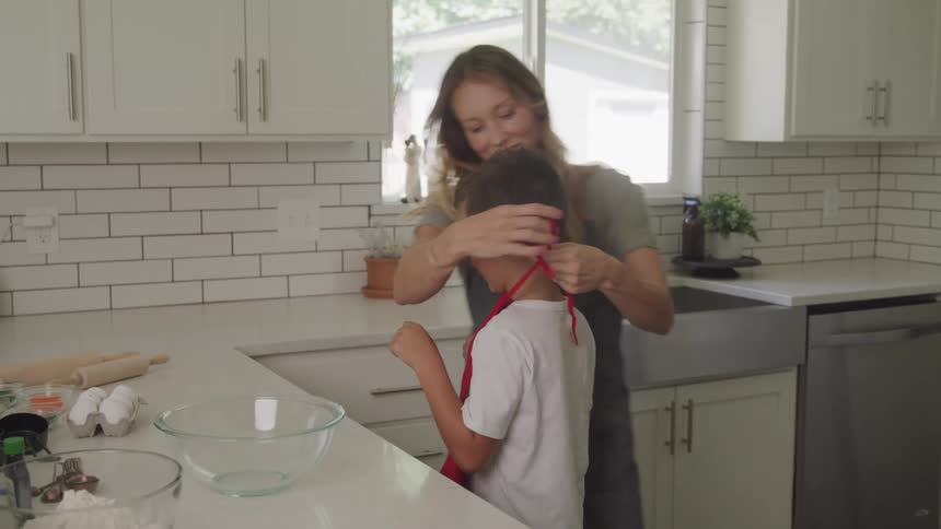 Mom puts apron on son to start cooking