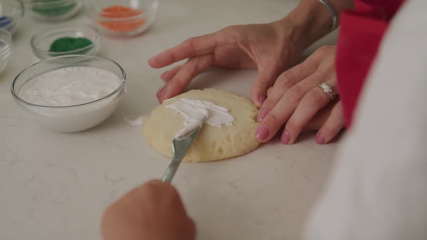 Hands spreading cream on cookies