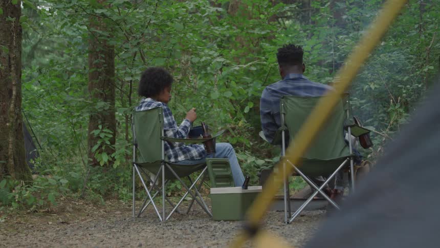 Couple sitting on lawn chairs having a picnic in the wilderness