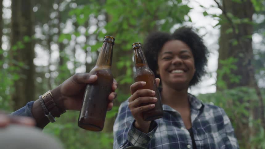 A footage of two friends drinking together at a campsite