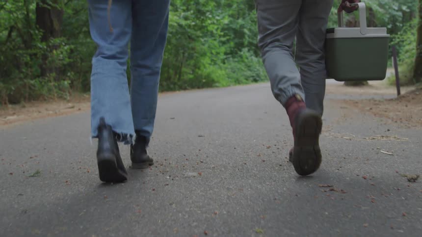 2 people walking in the woods with a container in their hands