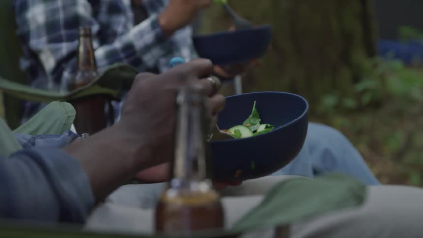 Couple sitting in the wilderness having a salad and beer for lunch