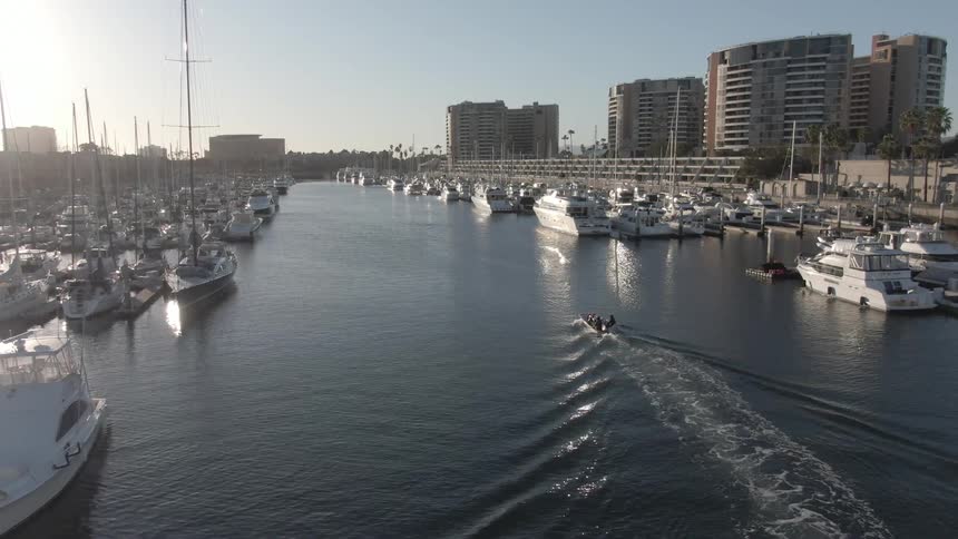 View of a harbor with boats docked and one crossing the waterway