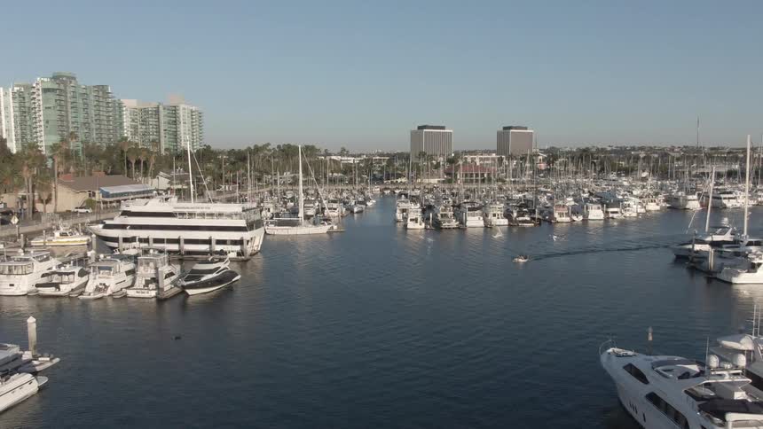 An aerial view of a boat traveling along the water outside a city harbor