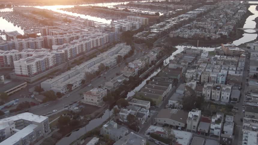 Red tinted sunlight illuminates roads passing through a residential neighborhood between a winding river and a marina