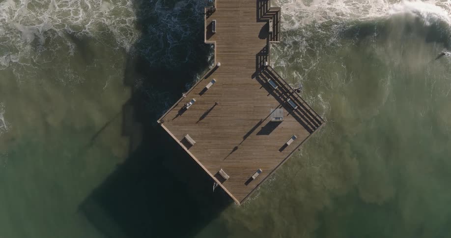 A surfer swims past the pier