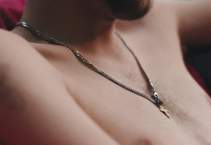 A man is wearing a cross on a necklace