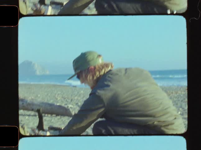 Man uses an ax to chop wood on the beach on a foggy day