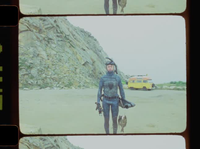 Man in a diving suit standing still holding a fish